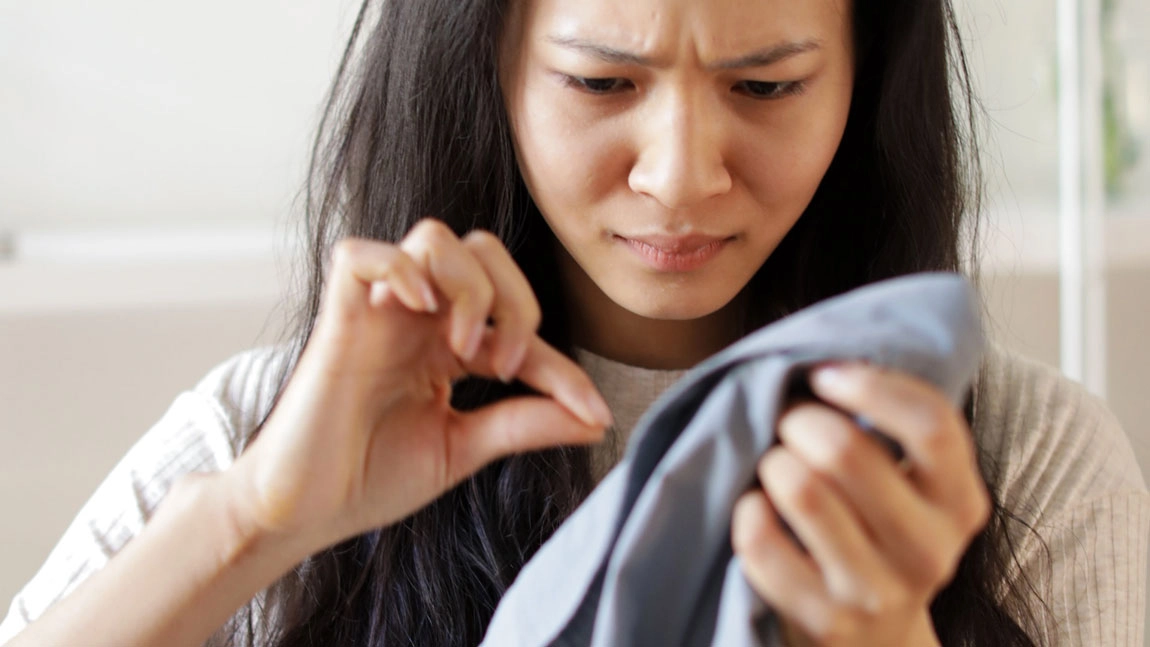 une jeune femme qui vient de repérer une abondante chute de cheveux sur ses vêtements